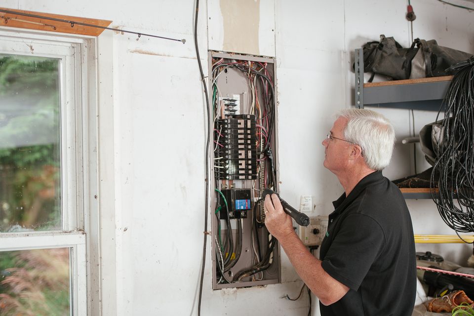 Stock view of an electrician inspecting a residential fuse box