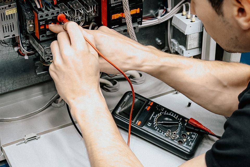 Stock close-up of an electrician testing an open panel with a multimeter
